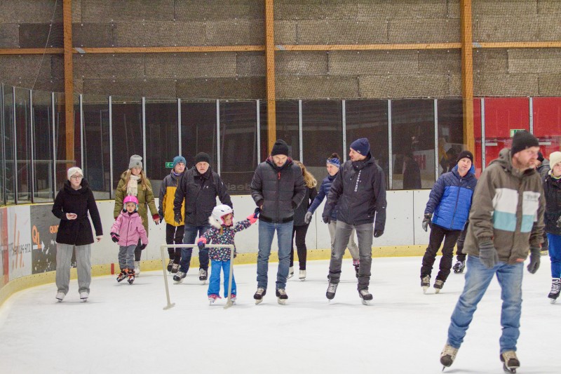 Na fotografii lidé bruslí na kluzišti a užívají si zimní atmosféru.